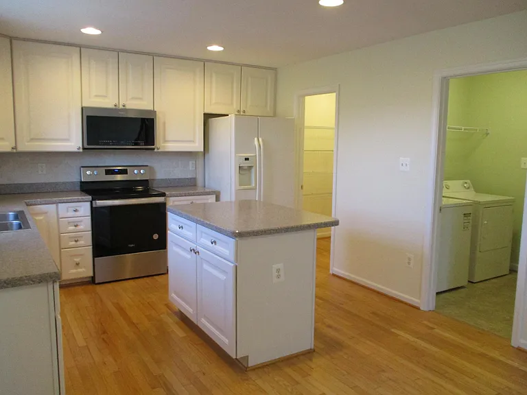 Opposite view of kitchen and entrance to large walk in pantry and large laundry room