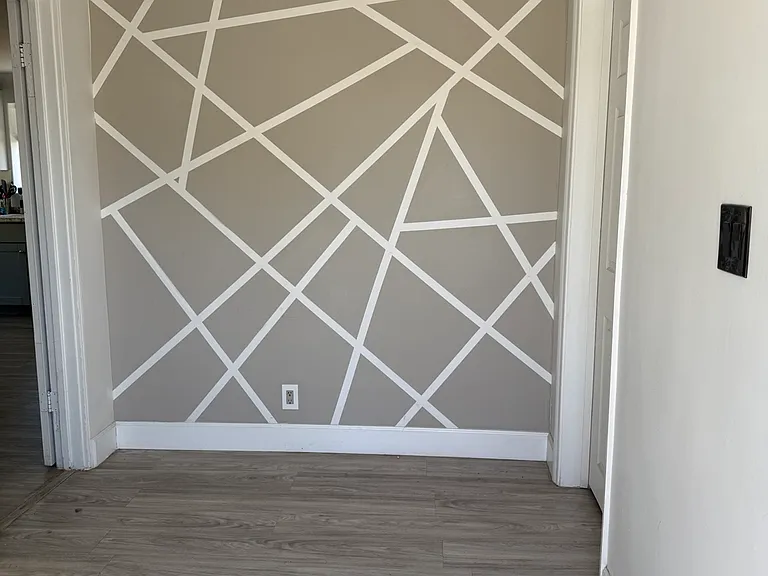 Modern entry foyer with custom geometric accent wall and updated flooring