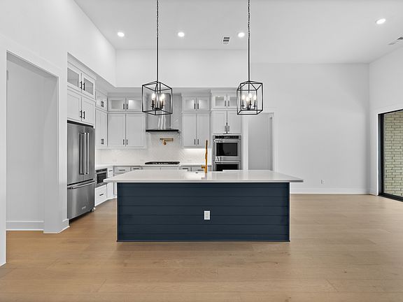 The kitchen has a beautiful blue island with quartz countertops.