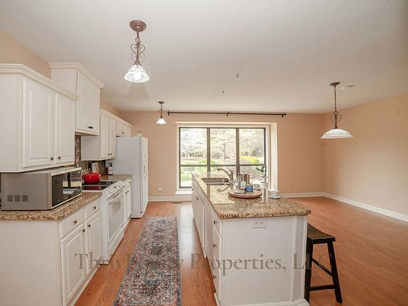Open-concept kitchen and dining area with granite countertops and front yard views..
