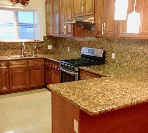 Large updated kitchen with breakfast island and marble flooring.