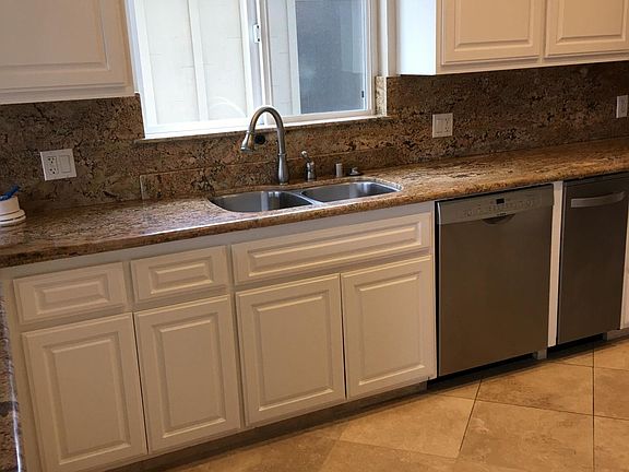Second story kitchen with stainless steel sink, dishwasher and trash compactor to the right.