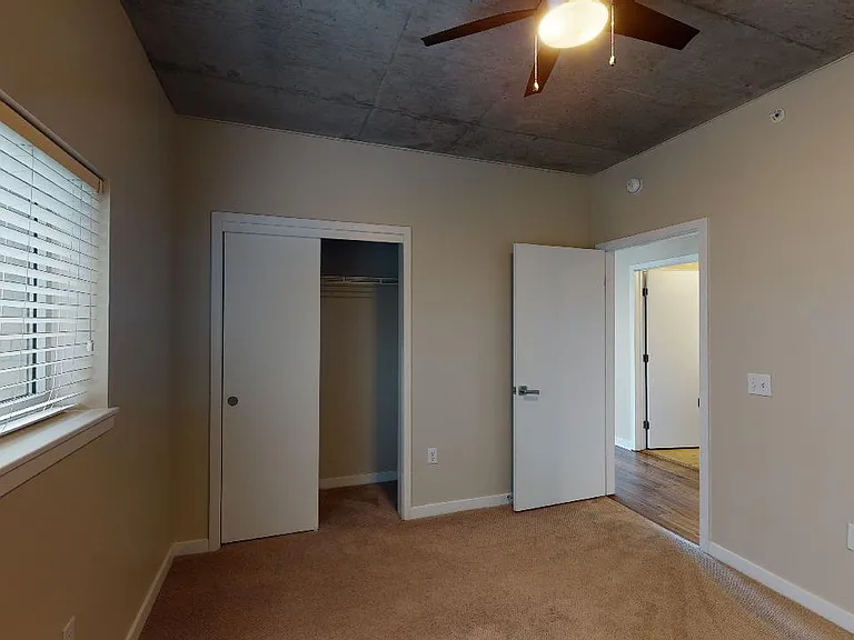 Spacious apartment bedroom with plush carpet flooring.