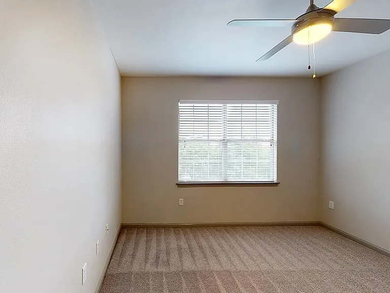 Apartment bedroom with carpet and light beige walls.
