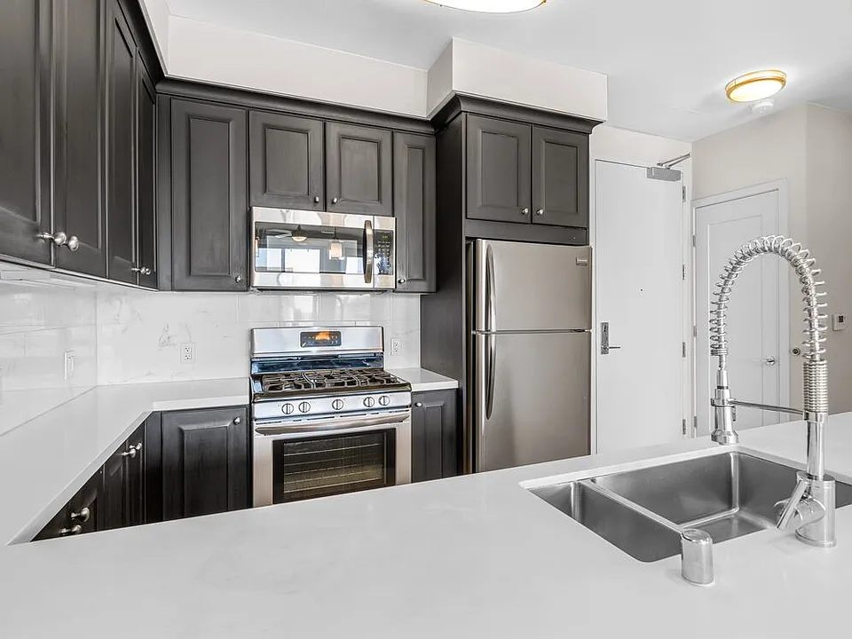 Kitchens with dark cabinetry, white quartz countertops, white tile backsplash, stainless steel appliances, and hard surface flooring