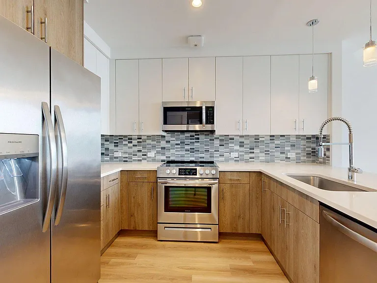 Apartment Kitchen with Stainless Steel Appliances and Wood-Style Flooring.