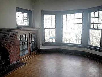 living room with built in bookcases and leaded glass window, non wood burning fireplace