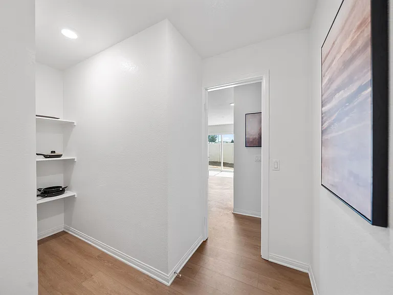 Clean hallway with wood-look flooring, built-in open shelving for extra storage, and easy access to the patio area.
