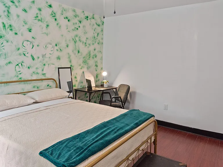 Furnished bedroom with a full bed, desk workspace, and an accent wallideal for studying and relaxing.