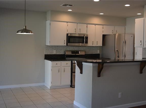 The dining area has a sleek new stainless steel light fixture to match the kitchen appliances