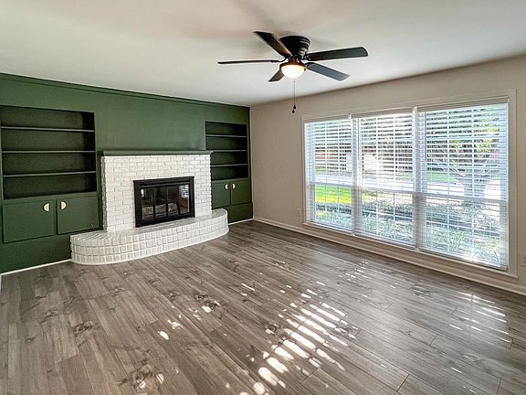 Living room area with a gas fireplace, lots of natural light, and built ins.