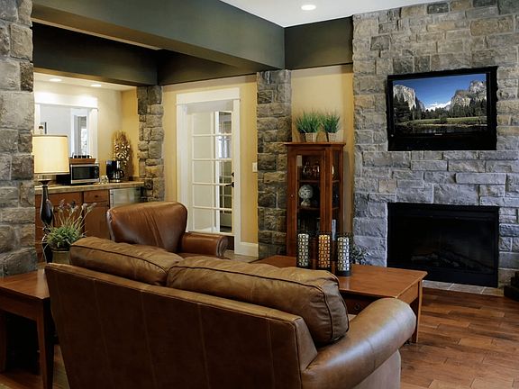Charming living room with rustic stone fireplace, leather seating, and elegant decor, creating a cozy and inviting atmosphere.