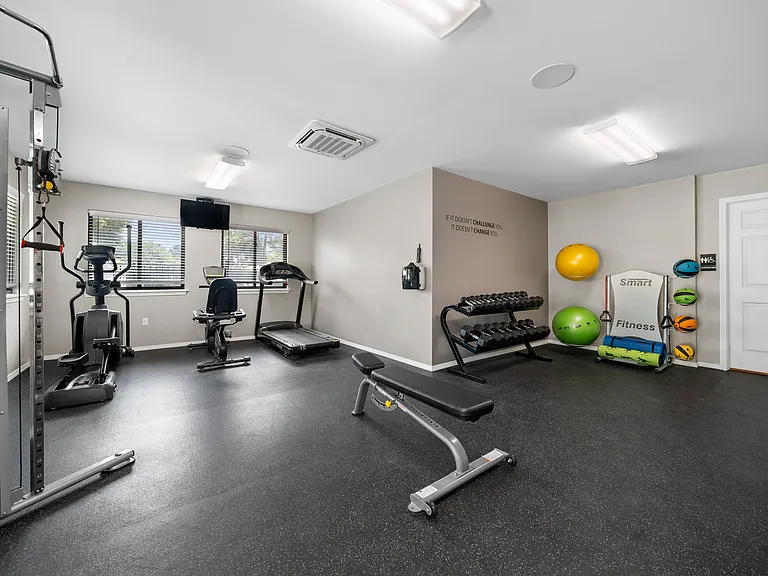 24-hour fitness center at cardio machines and weights at Woodland Villa Apartments in Westland, MI.