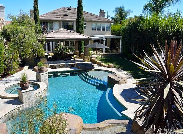 Backyard saltwater pebble tech pool and spa with waterfall and slide.