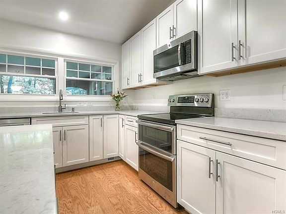 Brand new kitchen.  White shaker cabinets, soft close drawers, quartz countertops, stainless steel appliances, vaulted ceiling, recessed lights and hardwood floors.   Double oven shown in this photo. Stainless steel microwave and undercount sink.