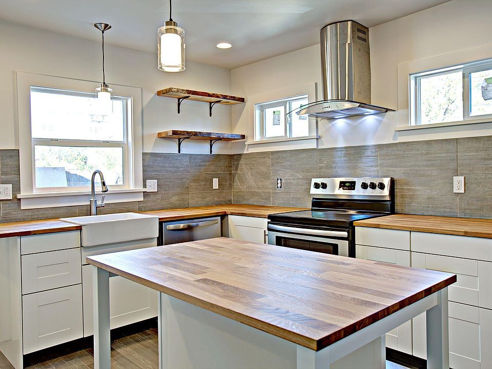 Beautiful kitchen with island/added storage, butcher-block countertops, apron-front sink, dishwasher, stainless steel refrigerator and range, tile backsplash, blue pine, live-edge shelves, large lazy susan and pantry