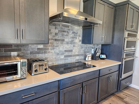 Induction stovetop and hood with beautiful cabinets and back splash