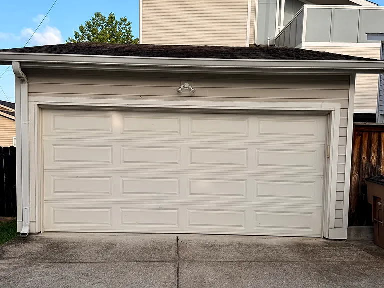 A two-car garage that is accessed by the alley. The light fixture over the garage, that has bulbs that will stay on from dusk to dawn