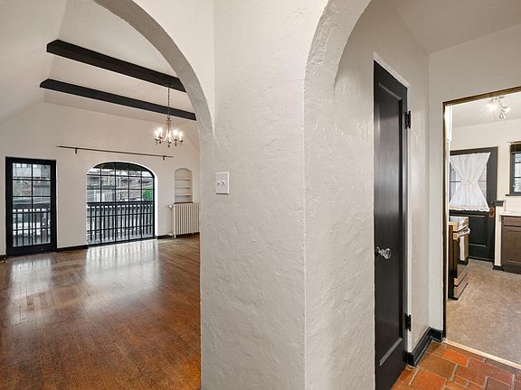 Main hallway with arched entries, view of the living room to a second hallway to the kitchen.