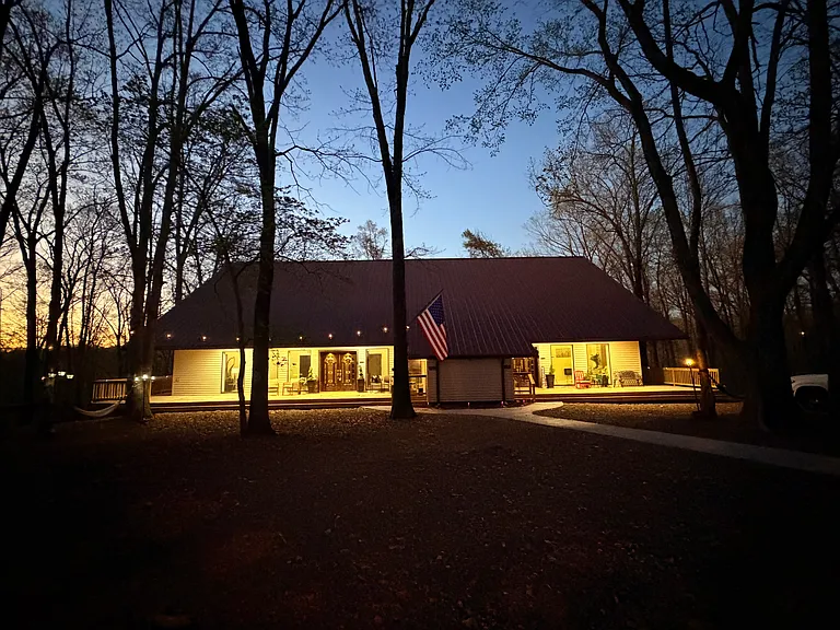 Magical After-Dark Curb Appeal | String-Lit Porch & Grand Entry As the Ozark sun sets, the property transforms. Warm string lights trace the porch, the ornate front doors glow like a lantern, and the forest wraps around you like a quiet embrace.