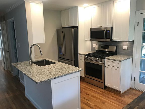 kitchen with granite counters, glass tile backsplash, stainless appliances, breakfast bar.