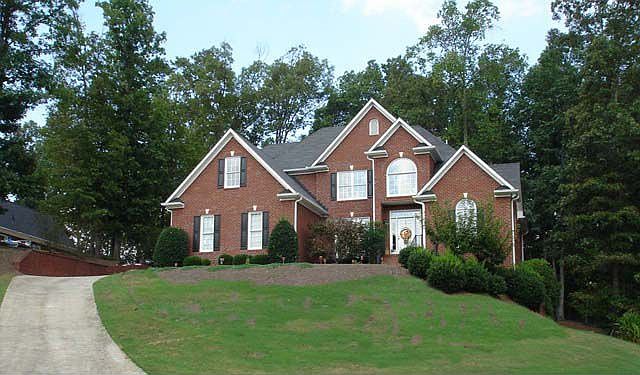 Four sided brick sits on a rise on a large wooded lot with a private back yard