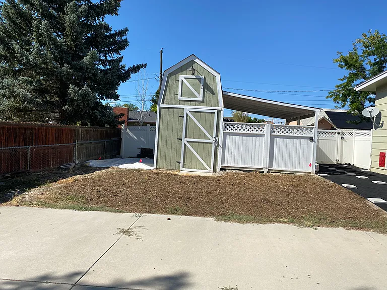 Storage shed and covered storage with stone entrance to the backyard.