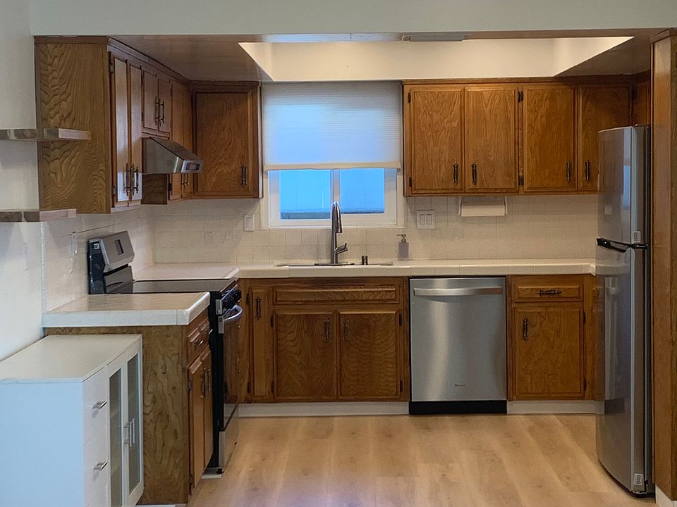 Open kitchen with ash cabinets, new electric range, new range hood, new dishwasher and new refrigerator freezer. New LED ceiling lighting in kitchen, dining area and living room.