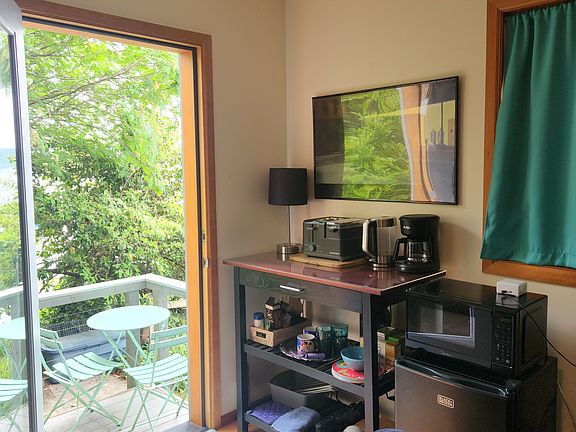 Kitchenette with breakfast station (toaster, egg poacher), microwave, min-fridge, food prep counter, cutting board, dishes, mugs, glasses, cutlery.