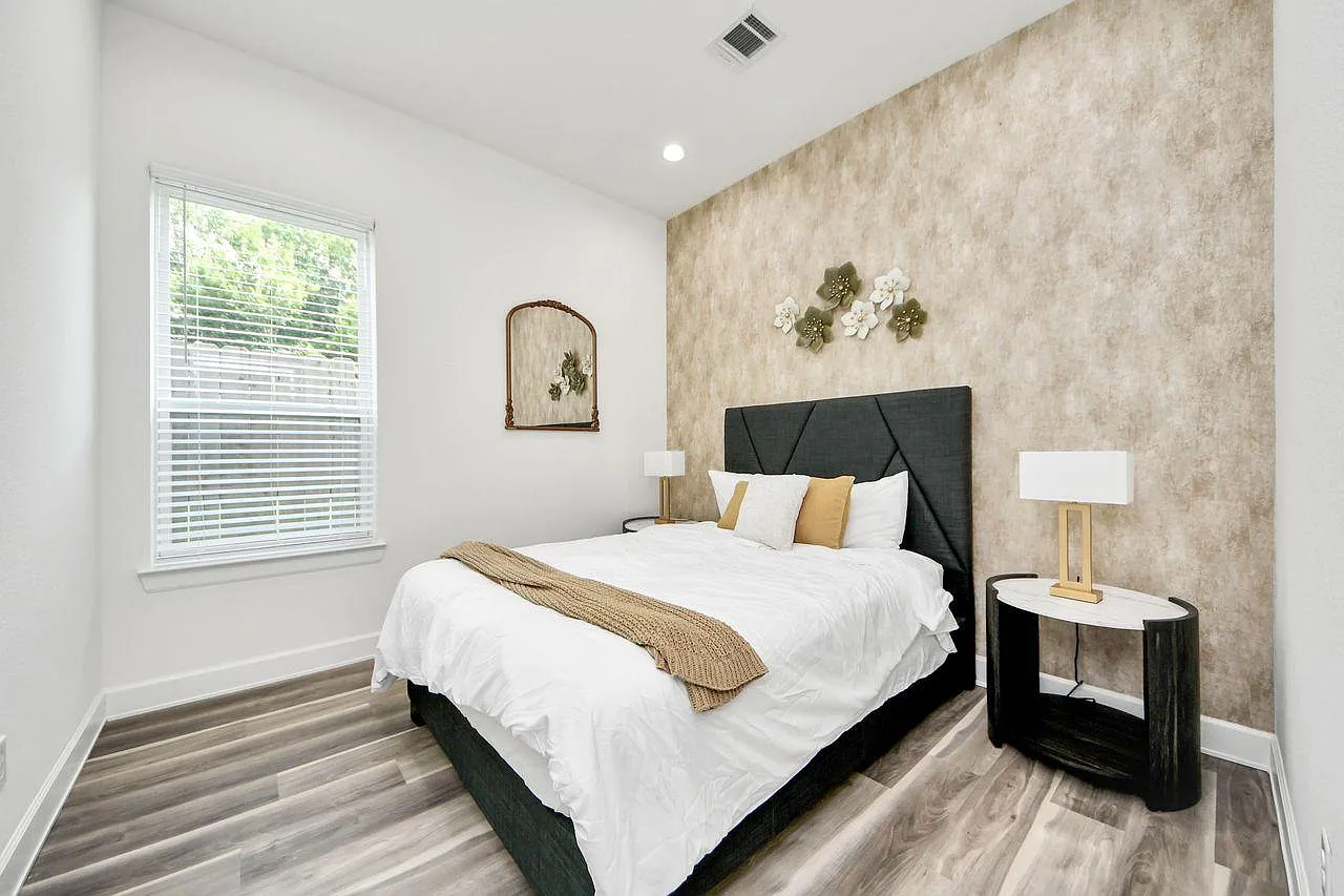 Private bedroom with a full bed, nightstands, and wood-look flooring, plus a window with blinds for natural light.