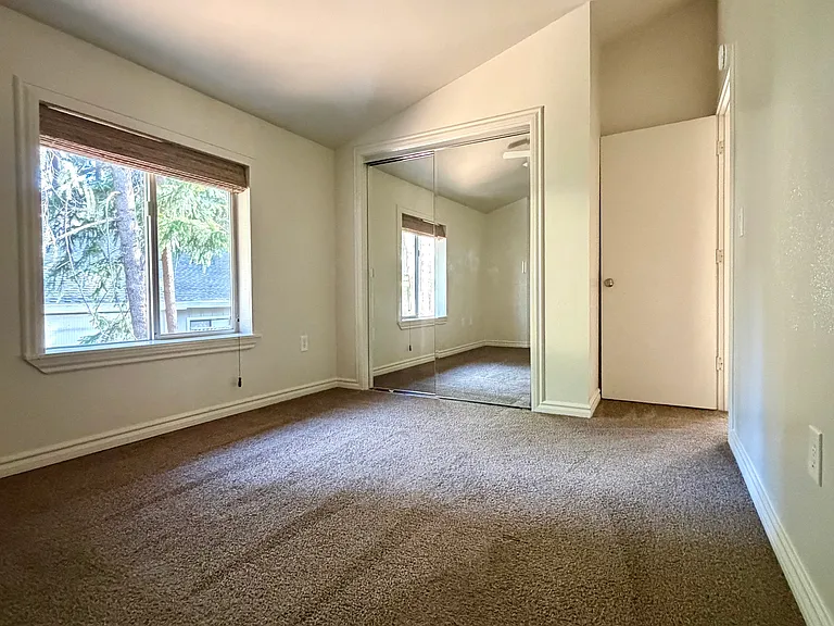 Bedroom #1 with mirrored closet, ceiling fan, and blackout shades