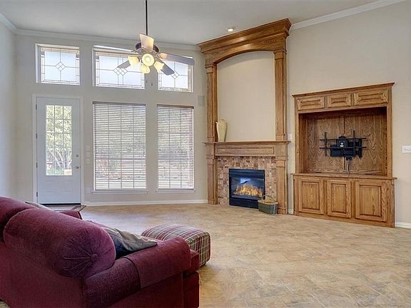 Family room with high ceiling, gas fireplace and builtin for audio and TV and view out to the pool.