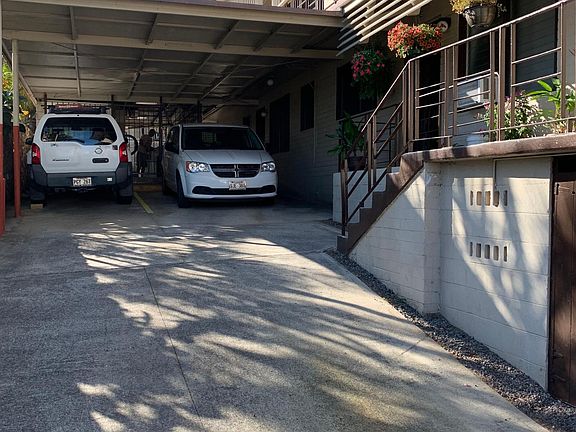 Driveway w/2 parking stalls in carport and laundry area behind cars.