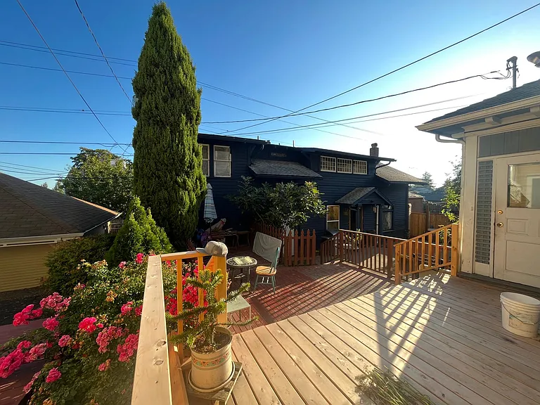 Backyard | Quiet two-level deck with afternoon sun, a patio with gas and charcoal grills, a small lawn, flower beds.