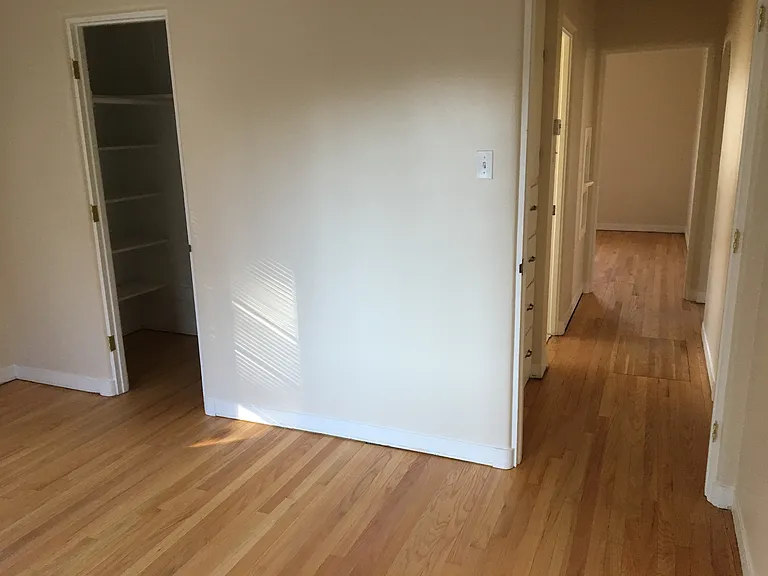 Empty second bedroom looking past bathroom and into first bedroom