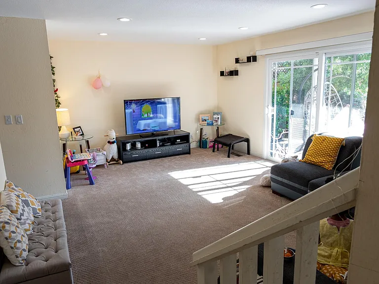 Family room with carpets before which have now been replaced with wooden flooring