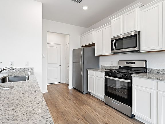 Chef-ready kitchen with stainless steel appliances, granite countertops, and white cabinetry.