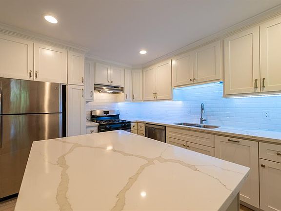 Completely renovated kitchen with stainless appliances, new cabinetry, beautiful backsplash, quartzite countertops, large island with storage underneath and beautiful lighting.