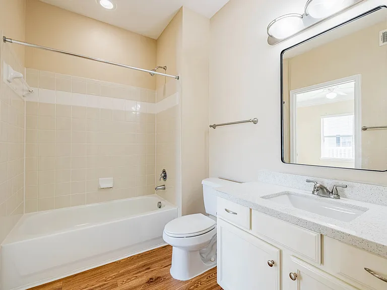 Bright and modern bathroom featuring a pristine white bathtub, sleek vanity with beautiful countertop, and elegant tile accents. Bright and modern bathroom featuring a pristine white bathtub, sleek vanity with beautiful countertop, and elegant tile accent