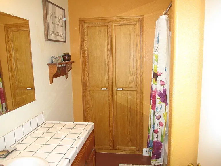 one sink bathroom with tub and different shower curtain. Lots of cabinet space.