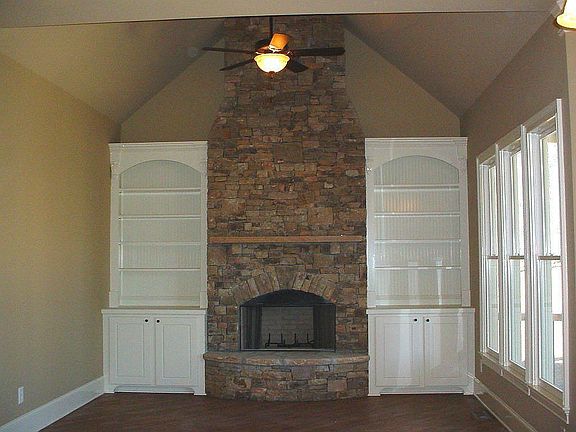 Vaulted keeping room has floor to ceiling stacked stone fireplace & built-ins.