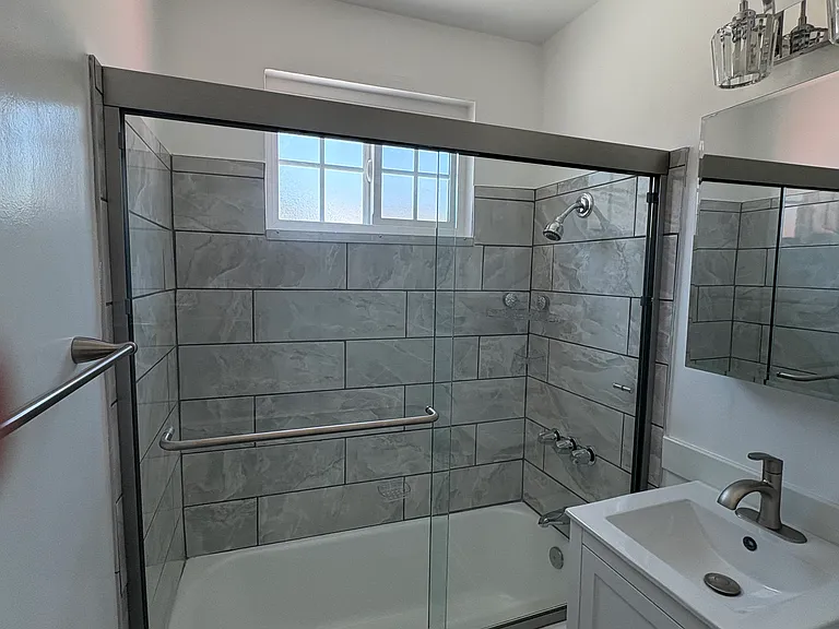 Newly remodeled bath with tub and enclosed shower.
