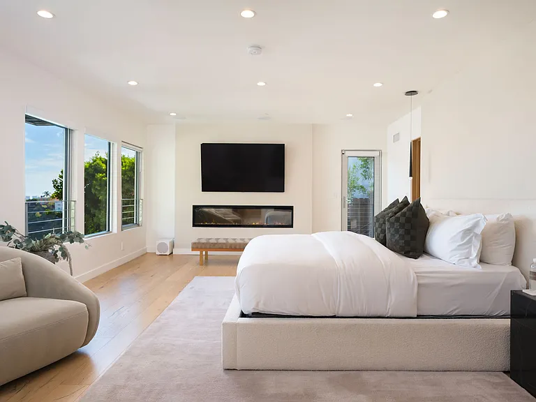 Primary bedroom, with 2 lounge chairs, large walk-in closet, en-suite bathroom, and electric fireplace.