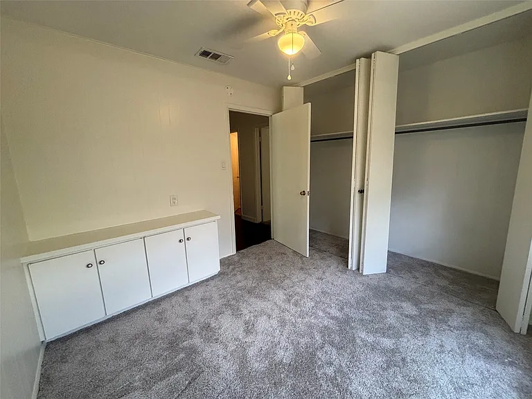 Carpeted interior room featuring a ceiling fan, built-in cabinetry, and integrated closet space