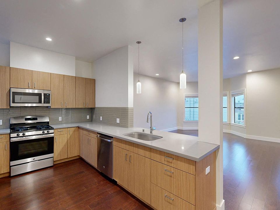 Kitchen with multiple cabinets, stove, sink, and a view of the living room