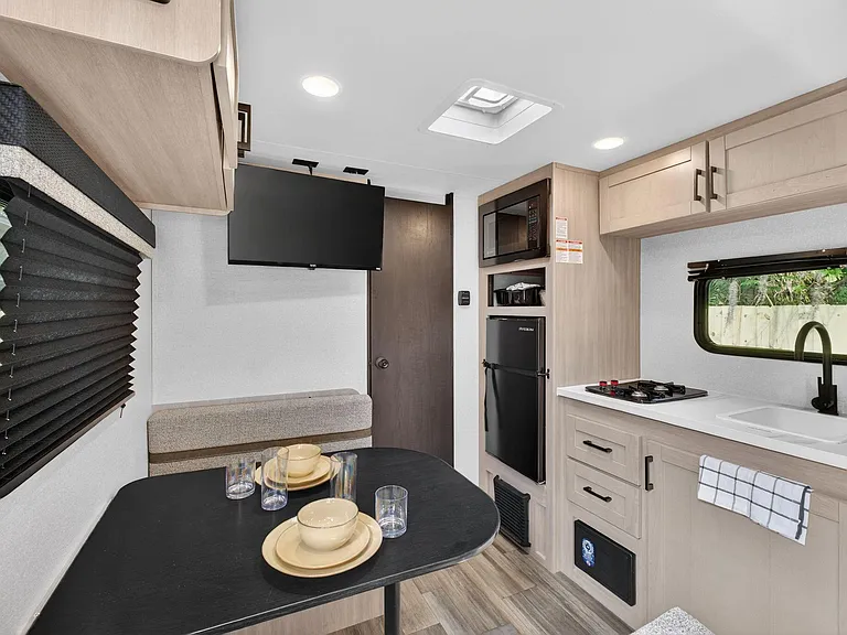 Efficient eat-in kitchen with sink, cooktop, fridge, and built-in microwave plus a dinette and wall-mounted TV.