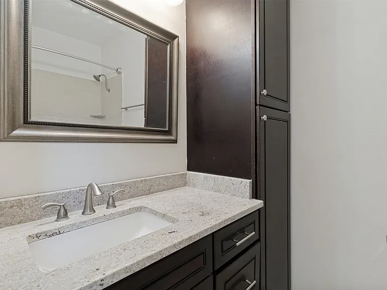 Vanity with a granite-style countertop, undermount sink, and brushed nickel fixtures