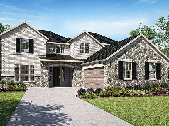 A large, two-story house with a stone exterior and a well-manicured lawn in the foreground, set agai