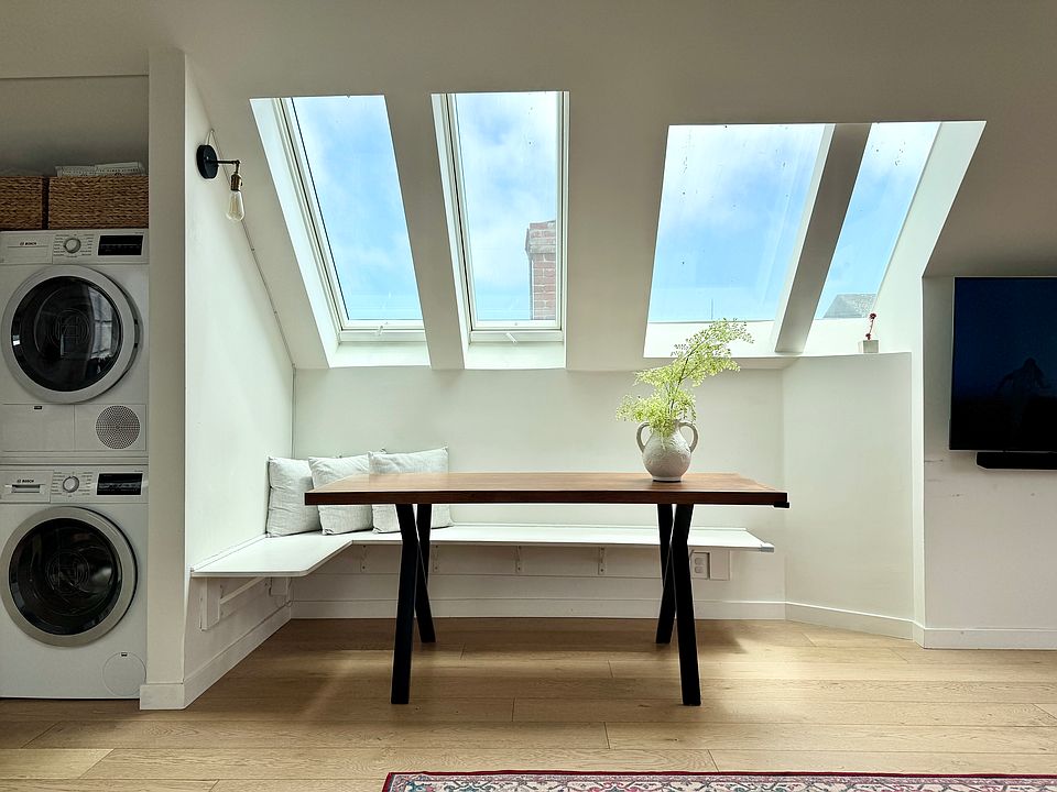 Dining area with built in seating and multiple skylights. Bosch washer drier in-unit.