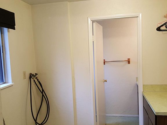 Laundry room showing cabinet and laundry hookups, and part of the downstairs half bath, seen from the kitchen